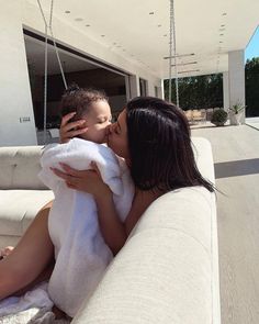 a woman kissing a man on the cheek while sitting on a white couch in front of a house