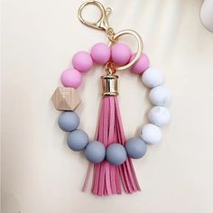 a pink and blue tasseled keychain hanging from a hook on a wall