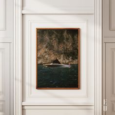 there is a painting hanging on the wall in front of a door that has an image of a boat