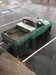 a green pick up truck parked in a parking lot