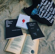 an open book sitting on top of a sandy beach next to a bottle of water