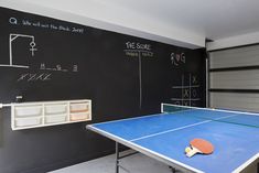 a ping pong table in front of a chalkboard wall