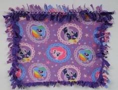 a purple square with pictures of pony ponies on it and fringes around the edges