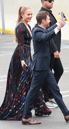 a man in a suit and tie walking next to a woman in a long dress