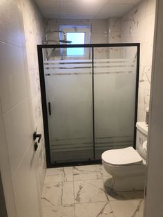 a white toilet sitting in a bathroom next to a walk in glass shower stall with sliding doors