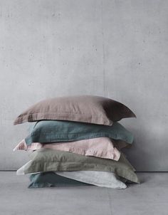 four pillows stacked on top of each other in front of a concrete wall and floor