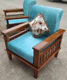 a blue chair sitting on top of a cement floor next to a wooden frame and pillow