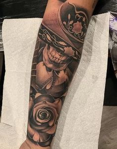 a man's arm with a skull and rose tattoo on the left side of his leg