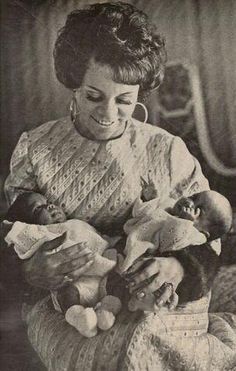 an old black and white photo of a woman holding a baby in her arms,