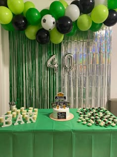 a table topped with lots of green and black balloons