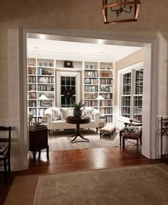 a living room filled with lots of furniture and bookshelves next to a doorway