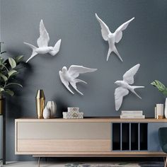 the birds are flying in the air on the wall above the tv stand and table