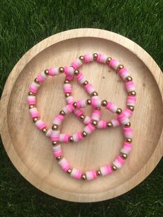 pink and gold beaded bracelets on a wooden plate with grass in the background