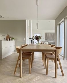 a dining room table with four chairs and a vase filled with flowers on top of it