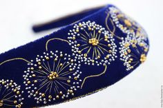 a blue headband with gold and white beading on it