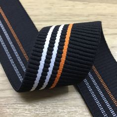 an orange, white and black striped tie on a wooden surface