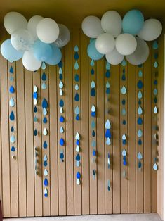 balloons and streamers are hanging from the wall in front of a door with wooden slats