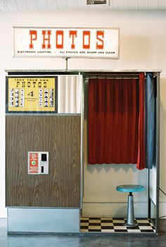 an old fashioned photo booth with red curtains and a blue table in front of it