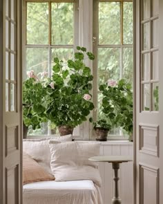 two potted plants sitting on top of a window sill next to a bed