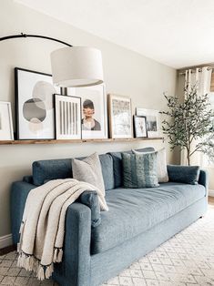 a living room with blue couches and pictures on the wall above them, along with other decor items