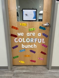 a bulletin board with words on it that says, we are a colorful bunch in front of an open door