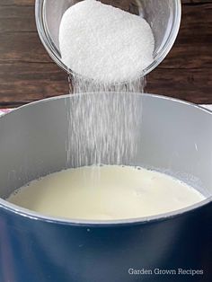 sugar being poured into a pot of milk