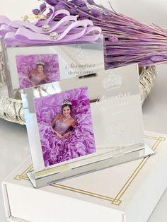 two cards that are sitting next to each other on top of a white box with purple ribbons