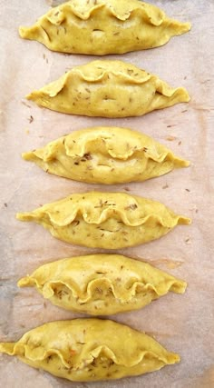 five uncooked pastries lined up on top of a piece of parchment paper