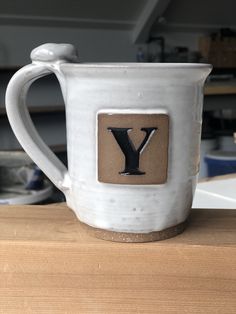 a white coffee mug with the letter y on it sitting on a wooden counter top