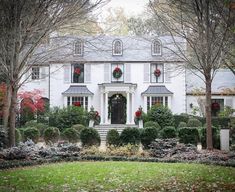 a large white house with wreaths on the windows and trees in front of it