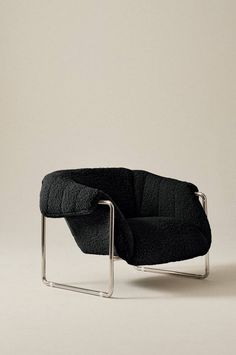 a black chair sitting on top of a white floor next to a gray wall with a metal frame