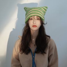 a woman wearing a green and white knitted hat with a blue ribbon around her neck