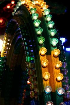 many lights are lit up on the side of a roller coaster at an amusement park