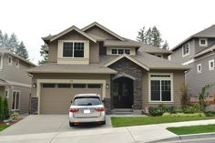 a car is parked in front of a house with two garages and three windows