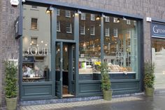 a store front with two people sitting at tables in the window and on the sidewalk