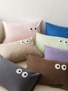 five pillows with eyes on them sitting on a bed