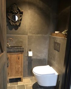 a bathroom with a toilet, sink and mirror on the wall next to tile flooring