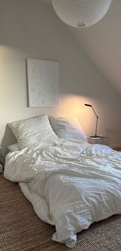 an unmade bed sitting in a bedroom next to two lamps on either side of the bed