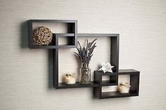 three square shelves on the wall with candles and flowers in vases next to each other