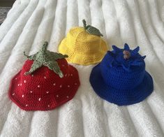 three crocheted strawberries sitting on top of a white bed next to each other