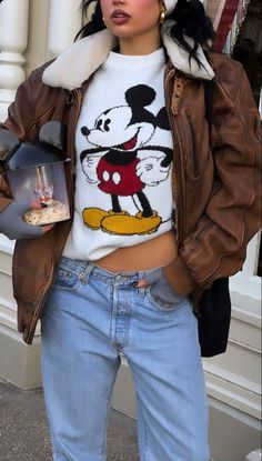 a woman wearing a mickey mouse sweater and jeans