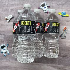 three plastic water bottles with rocket fuel labels on them and space themed magnets around them