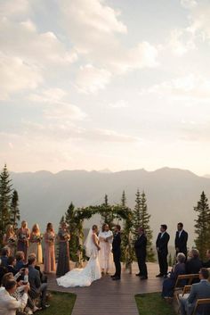 a bride and groom are getting married at the top of a mountain with their guests