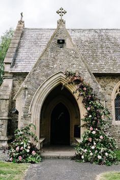 an old stone church with flowers growing on the front door and side entrance to it