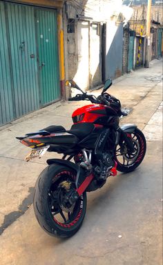 a red and black motorcycle parked on the side of a road next to a building