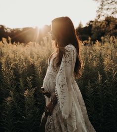 a woman in a white dress walking through tall grass