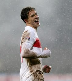 a soccer player is running in the rain with his mouth open and hands on his hips