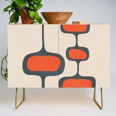 an orange and black cabinet with a potted plant on the top, next to it