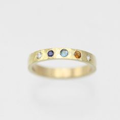 A colorful way to wear your family's birthstones! This ring is hand fabricated in solid 14ky gold and customized to use any number and combination of birthstones. The hammered texture gives the gold an extra glimmer! The ring is 3mm wide and 1.5mm thick. The stones are arranged in a straight line. Choose your ring size and desired number of birthstones when adding this item to your cart. Also, note the birthstone order from left to right in the text box. Please allow up to 14 business days for fabrication. Looks great stacked!!  Comes with a lifetime warranty, polishing cloth, and a gift box. All stones are synthetic except for Garnet, Amethyst, Peridot and Citrine which are natural. Feel free to ask for a price quote with all natural stones. Also available in sterling silver: https://www. 3 Birthstone Ring, 14k Yellow Gold Multi-stone Birthstone Ring, Multi-stone 14k Yellow Gold Birthstone Ring, Multi-stone Yellow Gold Birthstone Ring In 14k, Yellow Gold Multi-stone Birthstone Ring In 14k Gold, Anniversary Sapphire Ring With Recycled Gold, Recycled Gold Birthstone Ring For Promise, Yellow Gold Birthstone Ring In Recycled Gold, Promise Ring With Birthstone In Recycled Gold