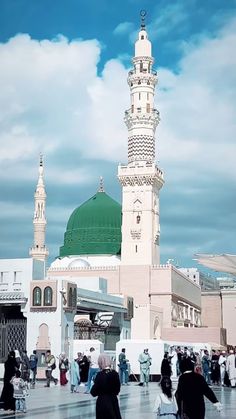 many people are walking around in front of a large white building with a green dome